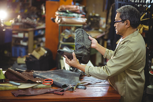 Shoemaker examining a leather boot in workshop
