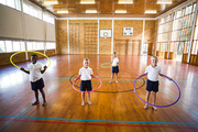 Students playing with hula hoop in school gym at elementary school
