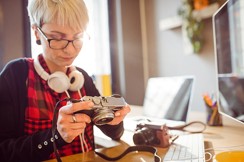 Female graphic designer looking at pictures in digital camera at office