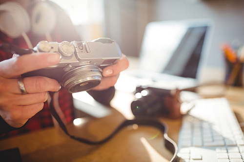 Mid section of female graphic designer holding digital camera at office