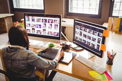 Female graphic designer using graphic tablet while working on computer at office