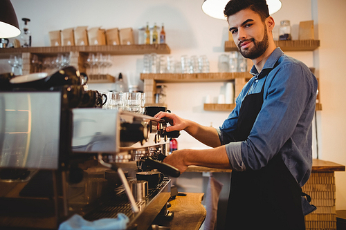 Portrait of young man taking coffee from espresso machine at office cafeteria