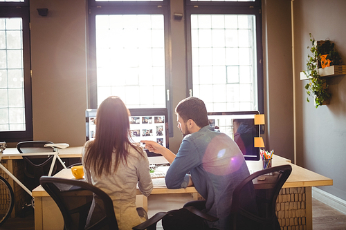 Rear view of graphic designers working at desk in the office