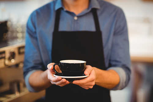 Mid section of man holding cup of coffee in office cafeteria