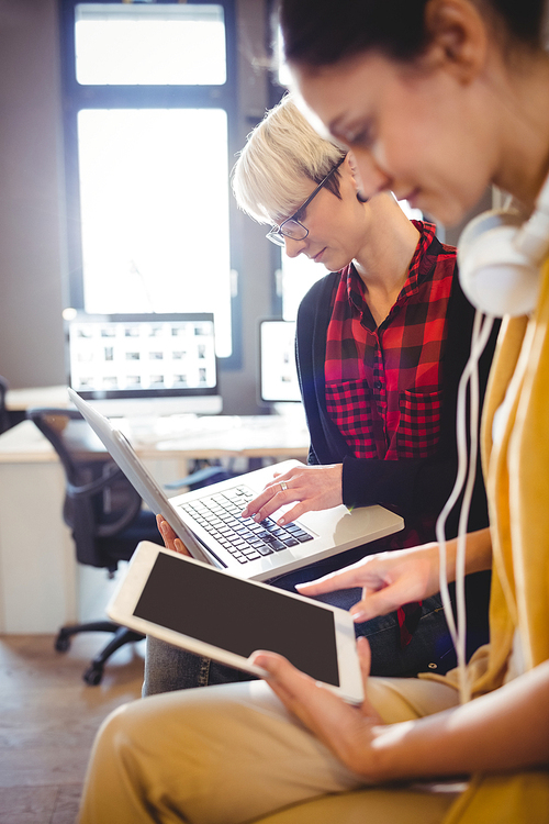 Two female graphic designer using digital tablet and laptop in office