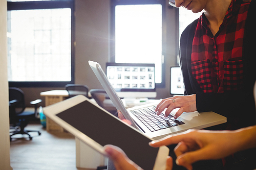 Two female graphic designer using digital tablet and laptop in office