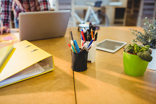 Pen holder with pens and file on table at office