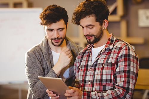 Graphic designer using digital tablet with his coworker in the office