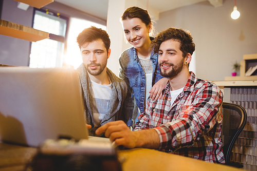 Graphic designer using laptop with his coworker in the office