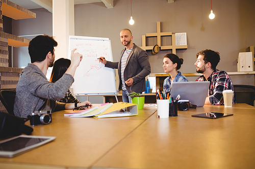 Male graphic designer discussing chart on white board with coworkers in the office