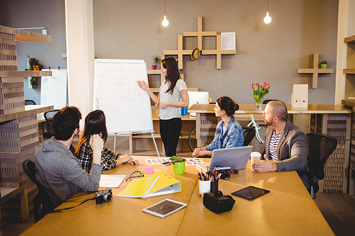 Female graphic designer discussing chart on white board with coworkers in the office