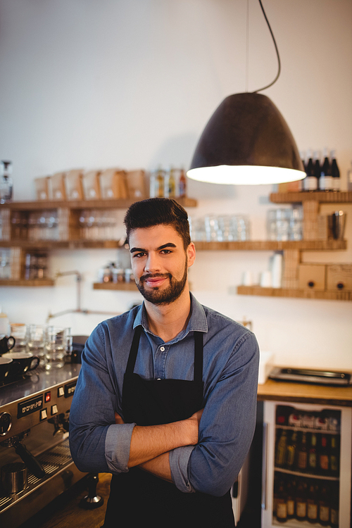 Portrait of young man with arms crossed in office cafeteria