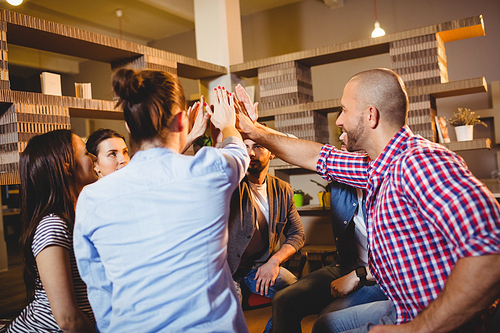 Colleagues giving high five during meeting at office