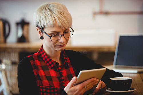 Woman using digital tablet while having coffee at office cafeteria