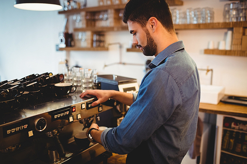 Young man taking coffee from espresso machine at office cafeteria