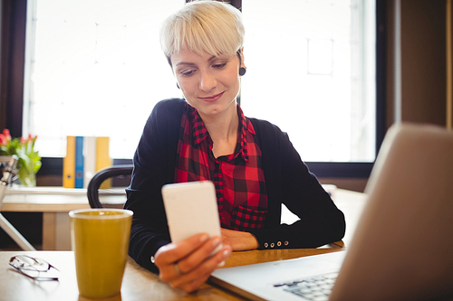 Beautiful young woman using mobile phone at office