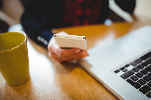 Mid section of woman using mobile phone at office