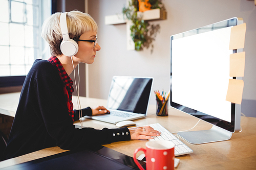 Female graphic designer working on computer and laptop at office