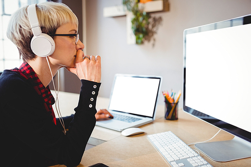 Female graphic designer working on computer and laptop at office