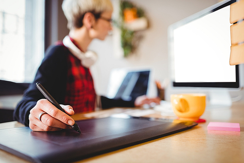 Female graphic designer using graphic tablet at office