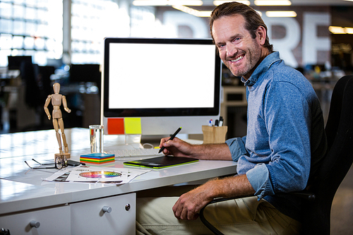 Portrait of happy photo editor working with graphics tablet in creative office