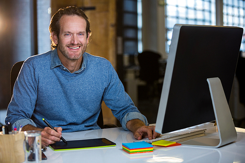 Portrait of confident photo editor working at desk in creative office