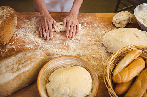 Hands of female baker kneading a dough in bakery shop