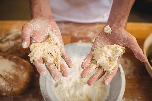 Hands of baker mixing flour by hand at bakery shop