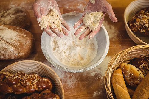 Hands of baker mixing flour by hand at bakery shop