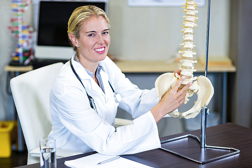 Portrait of smiling physiotherapist holding a spine model