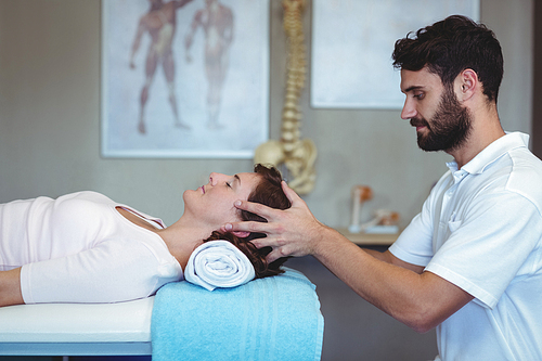 Physiotherapist giving head massage to a woman in clinic