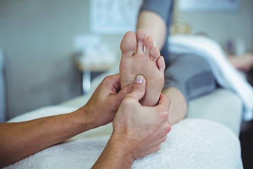 Physiotherapist giving foot massage to a woman in clinic