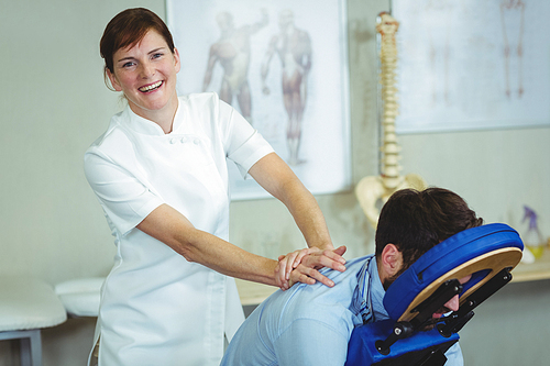 Portrait of physiotherapist giving back massage to a patient in the clinic