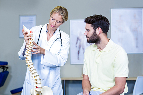 Physiotherapist explaining the spine model to patient in the clinic