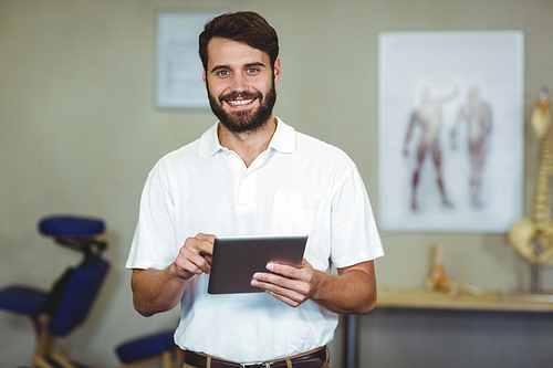 Portrait of male therapist holding digital tablet in clinic