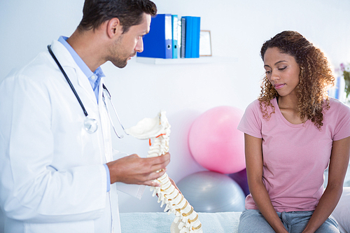 Physiotherapist explaining spine model to patient in clinic