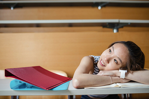 Thoughtful young woman leaning on bench in classroom at college