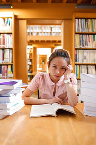 Portrait of tensed young woman studying in library at college