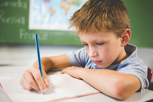 Schoolboy doing homework in classroom at school