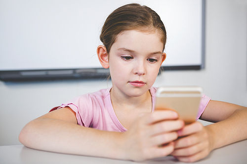 Schoolgirl using mobile phone in classroom at school