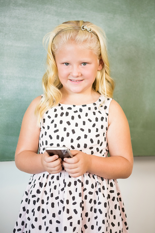 Portrait of schoolgirl using mobile phone in classroom at school
