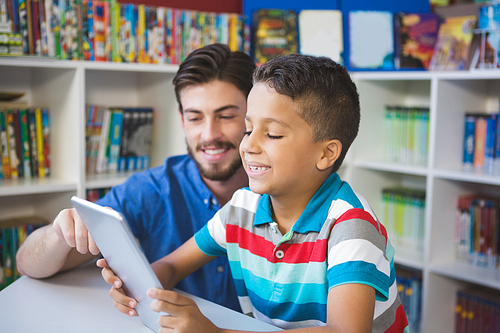 Teacher and school kid using digital table in library at school