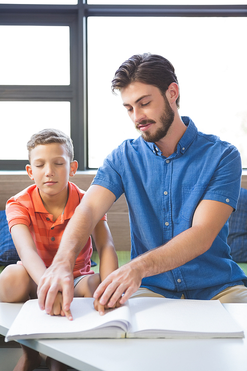 Teacher assisting blind student in library at school