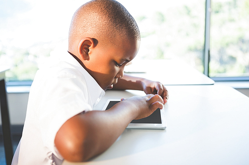 Close-up of schoolkid using digital tablet in classroom at school