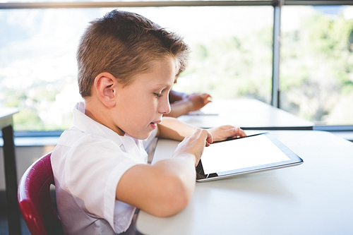 Close-up of schoolkid using digital tablet in classroom at school