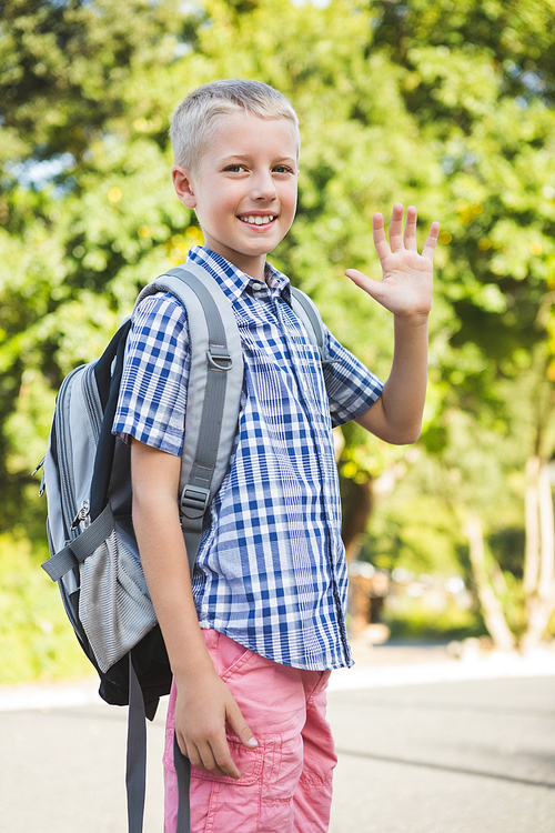 Portrait of happy schoolkid waving hand in campus