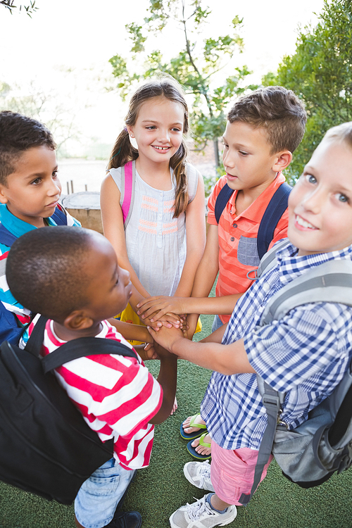 Schoolkids putting their hands together in campus at school