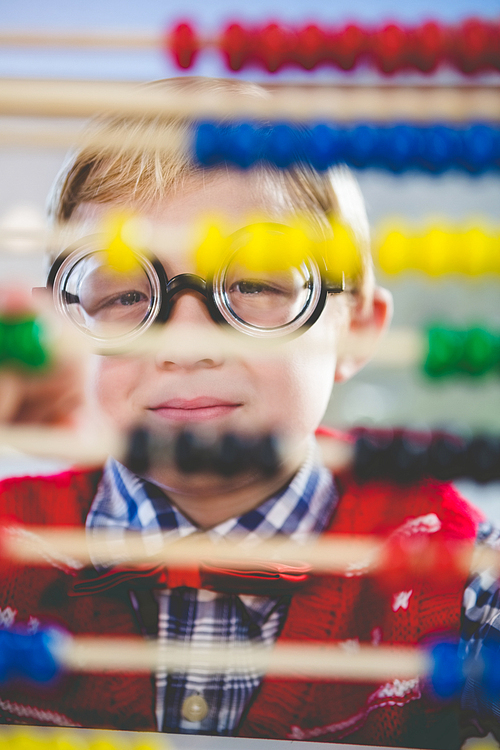 Close-up of schoolkid looking through abacus in classroom at school