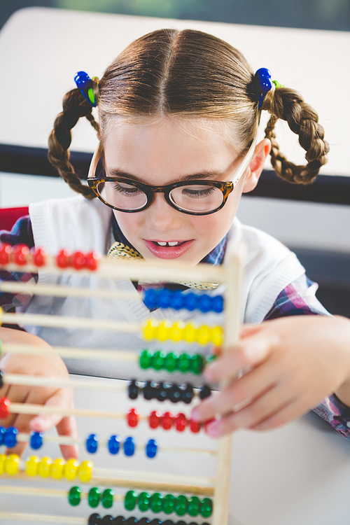Close-up of schoolkid counting abacus in classroom at school