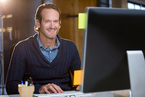 Portrait of confident businessman using computer at desk in office